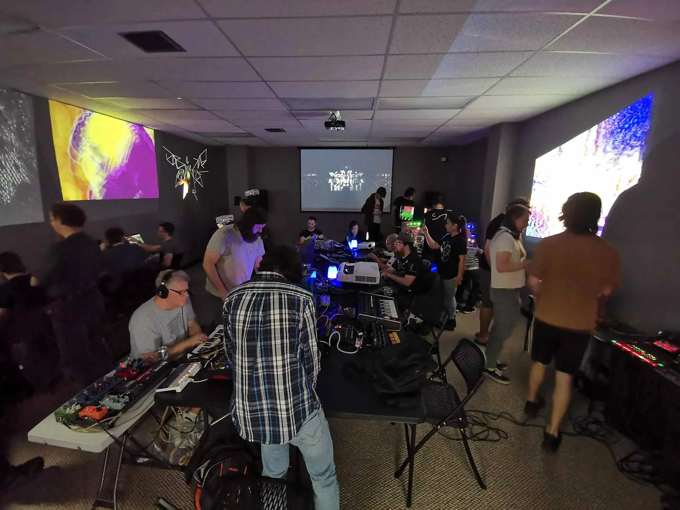 Several musicians gathered around a table of synthesizers at a Circuit Church synth meetup